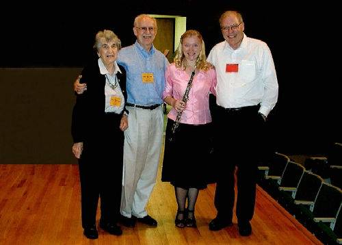 A photo of four people standing on a stage.